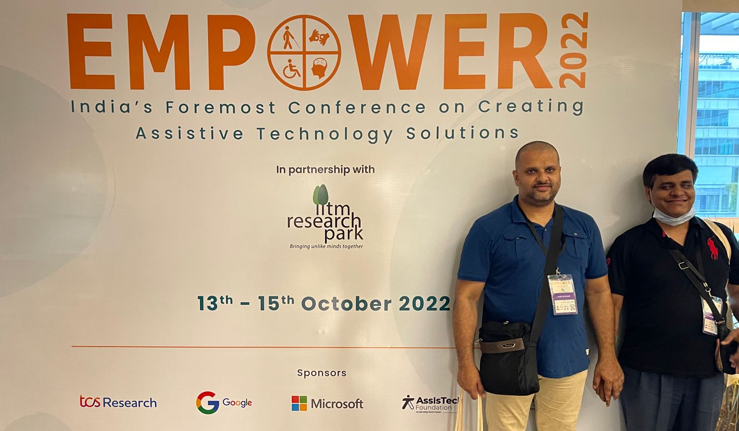 Sunil and Pradip standing in front of Empower 2022 Conference banner